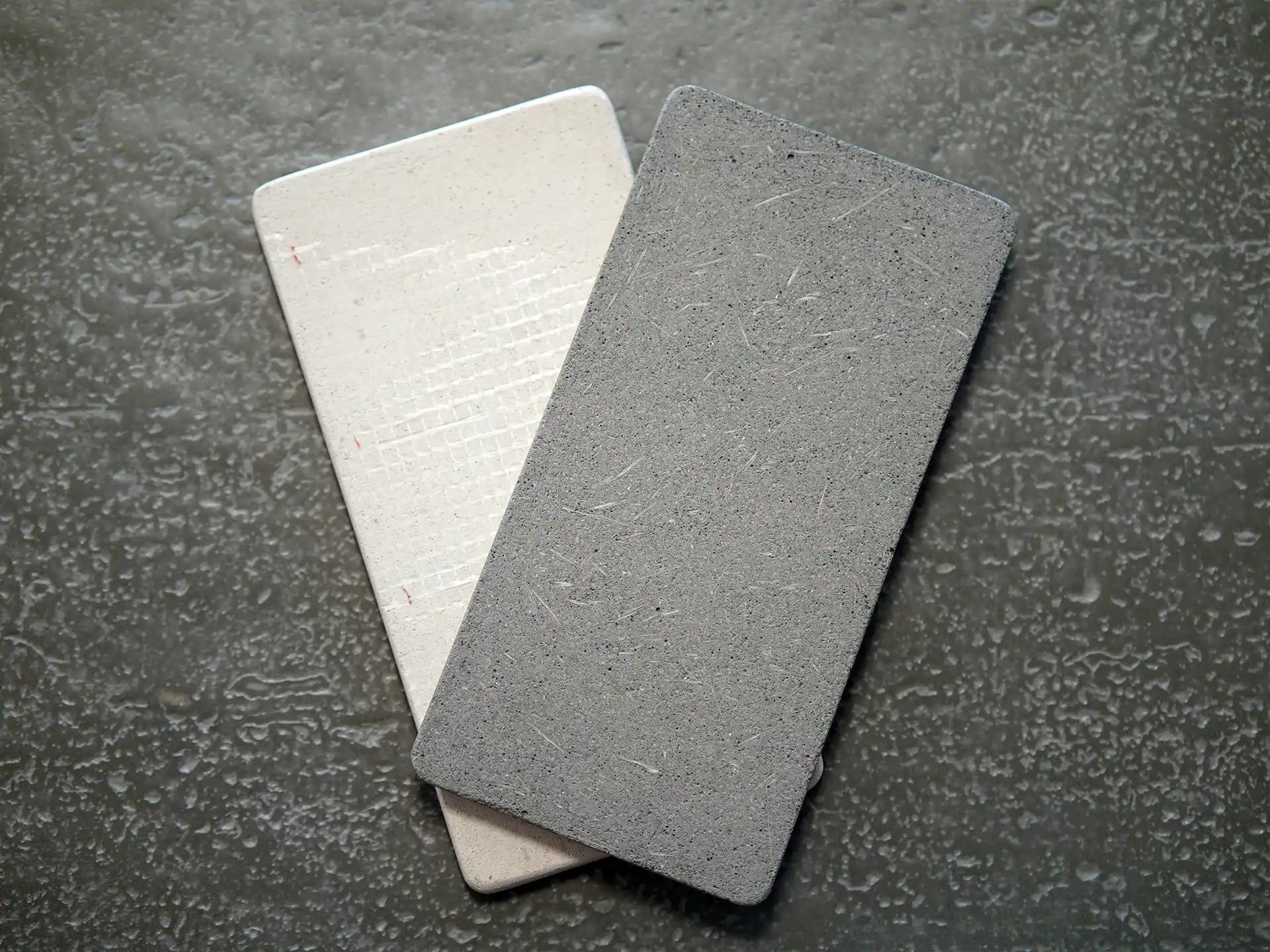 Macro of the cast surface: fine aggregate, sand tone, matte finish in raking light. Shows that colour runs through the material.